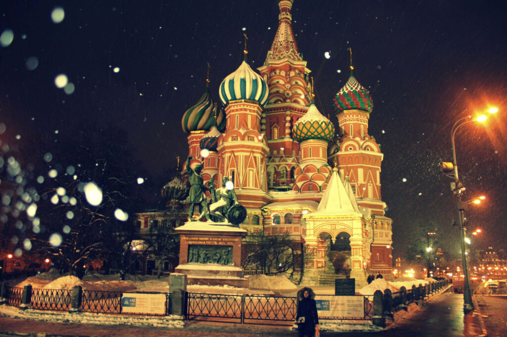 Illuminated Kremlin and St Basil's Cathedral in Moscow at night with falling snow wallpaper