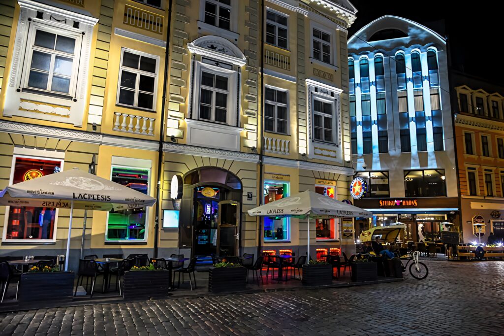 Vibrant night cafe street in Riga with glowing lights historic buildings colorful reflections Wallpaper