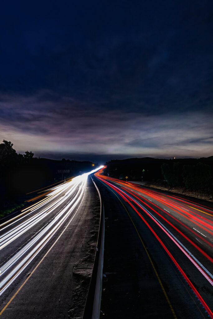Nighttime highway with vibrant headlight and taillight trails under deep blue sky wallpaper background