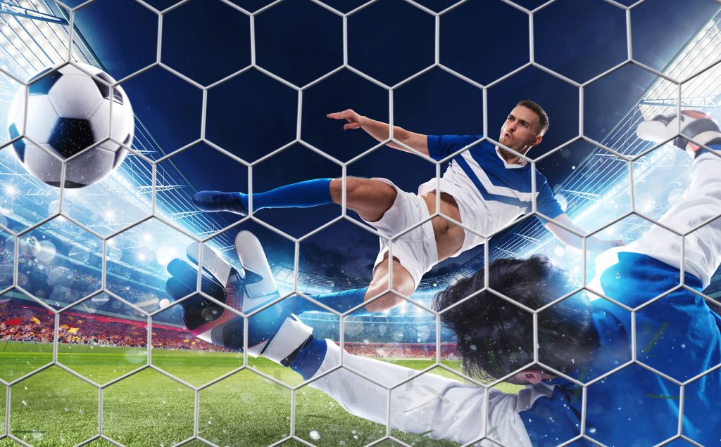 Soccer player bicycle kick shot blocked by goalkeeper at night stadium viewed through net wallpaper
