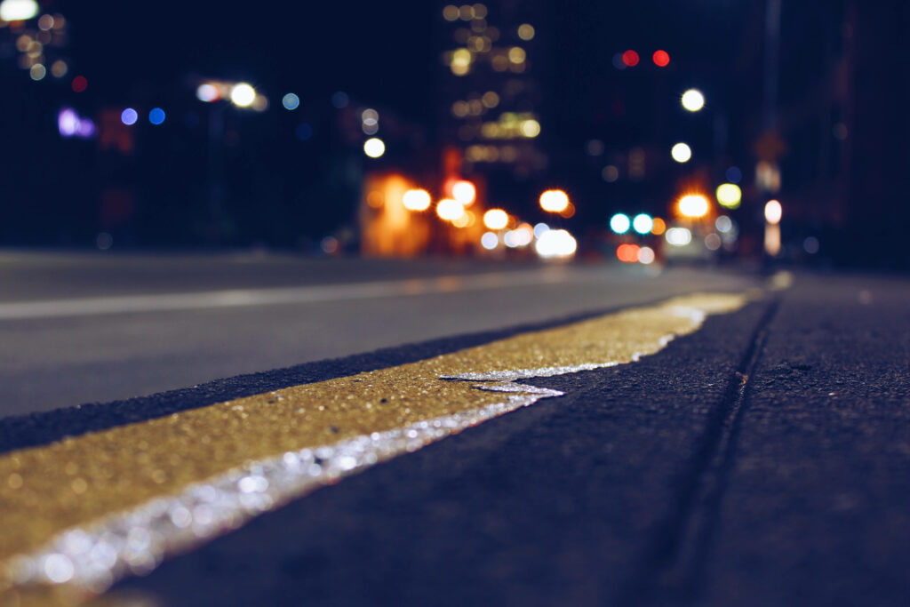 Nighttime Blurscape: A Low Angle View of a Vibrant City Street Wallpaper