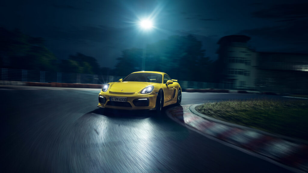 Yellow Porsche Cayman GT4: Nighttime Racetrack Reflection Wallpaper