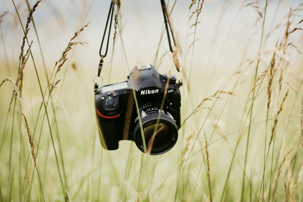 Nikon Camera in Tall Grass: Nature Meets Modern Technology Wallpaper