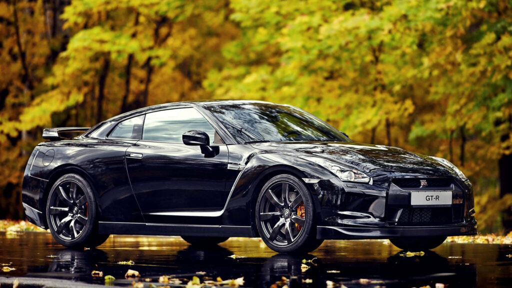 Black Nissan R35 GTR Black Edition parked by vibrant autumn forest showcasing bold design Wallpaper