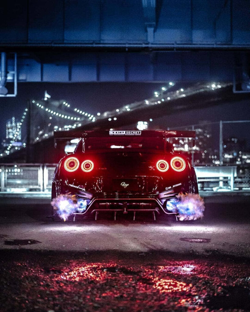 Nissan R35 GTR rear night shot with iconic taillights and blue flames under city lights wallpaper