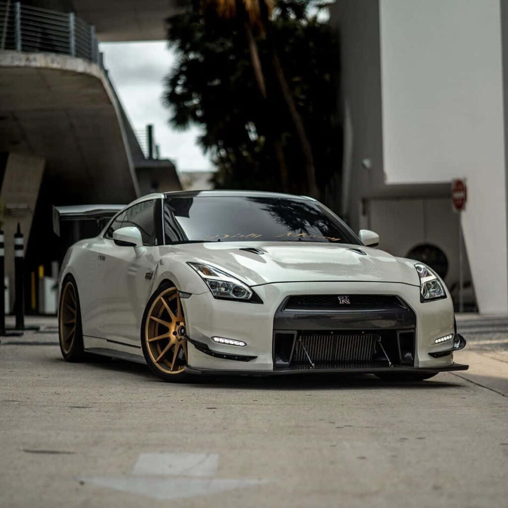 Nissan R35 GTR parked on city street with custom gold wheels and aggressive front splitter wallpaper