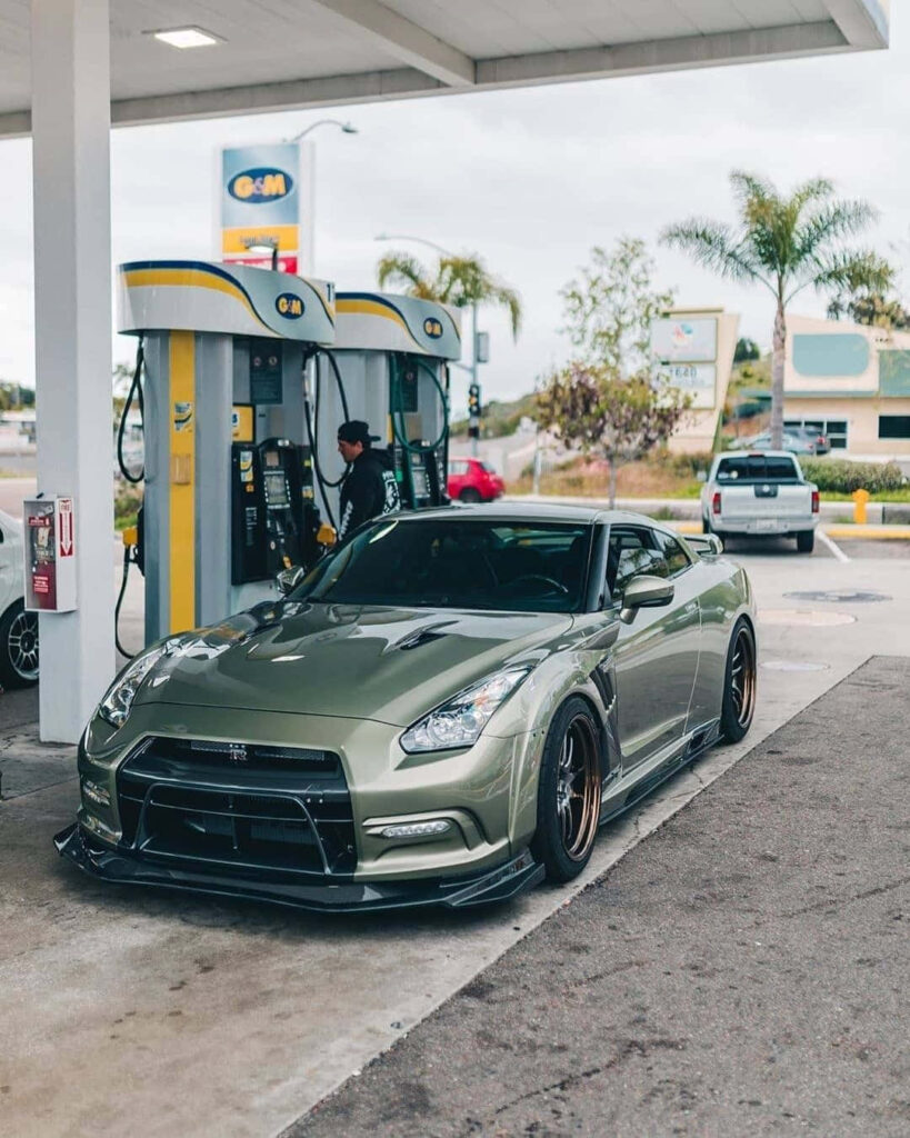 Sleek Nissan R35 GTR with aggressive body kit parked at gas station under cloudy sky wallpaper