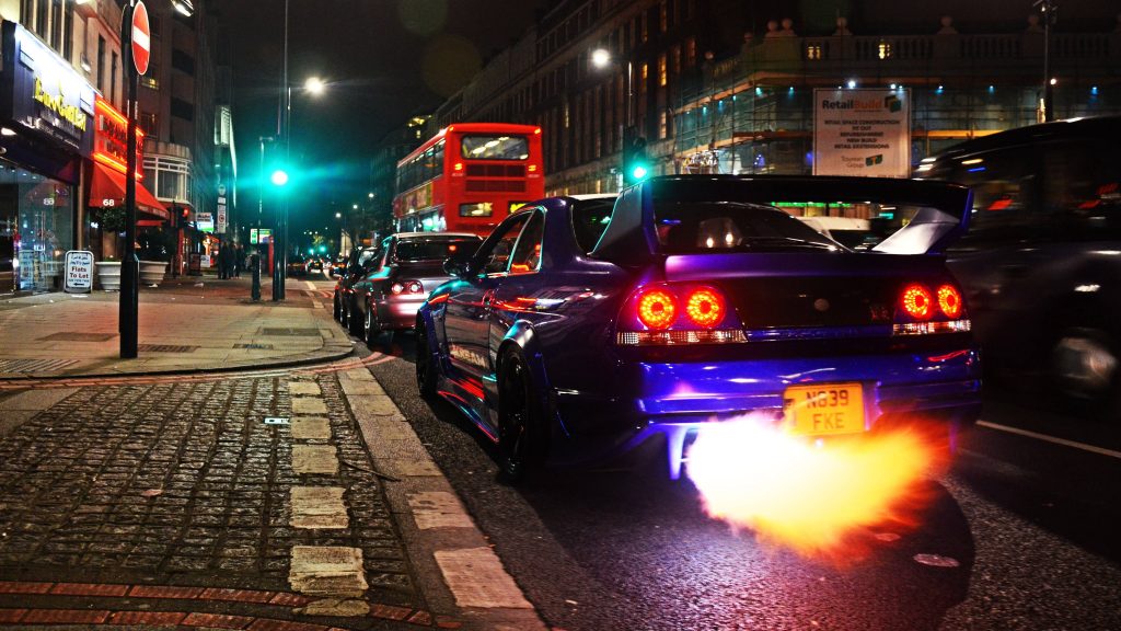 Nissan Skyline GT-R R33 deep blue JDM car speeding with flame exhaust on dark London street night Wallpaper