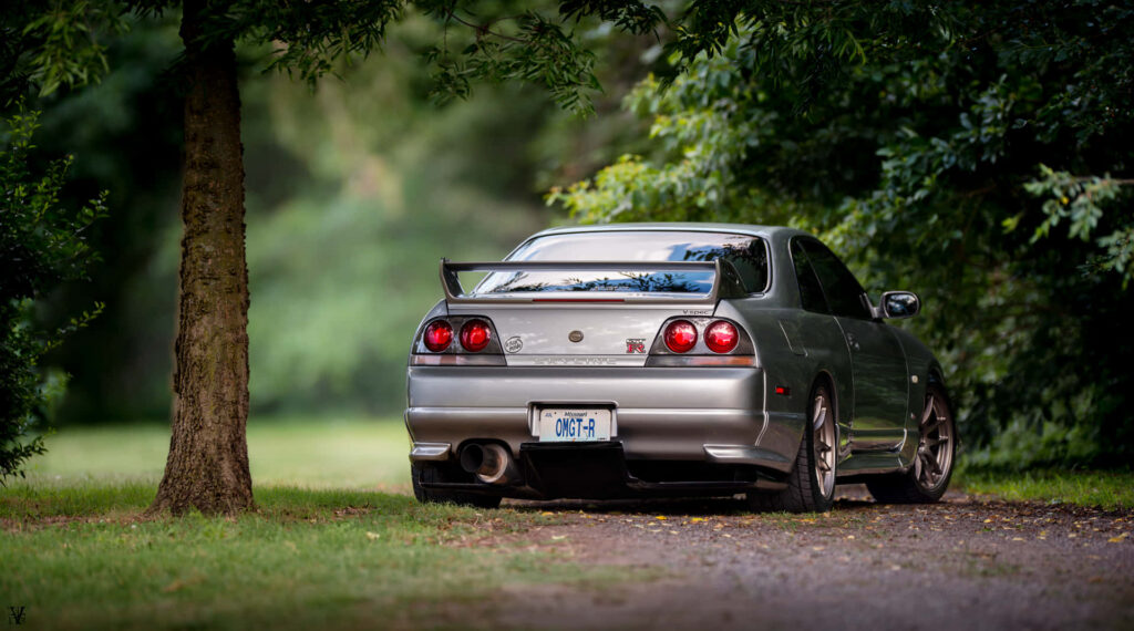 “Iconic Nissan Skyline R33 GT-R Wallpaper in Lush Green Setting”