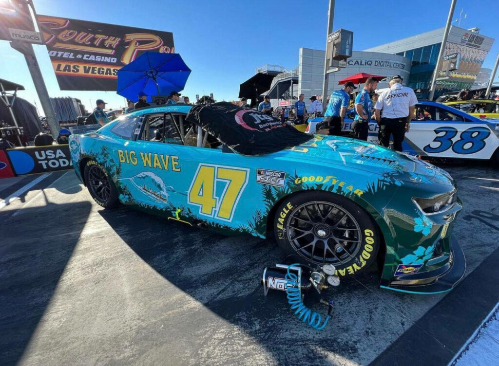Bright blue No 47 Big Wave race car driven by Ricky Stenhouse Jr on pit road sunny sky wallpaper