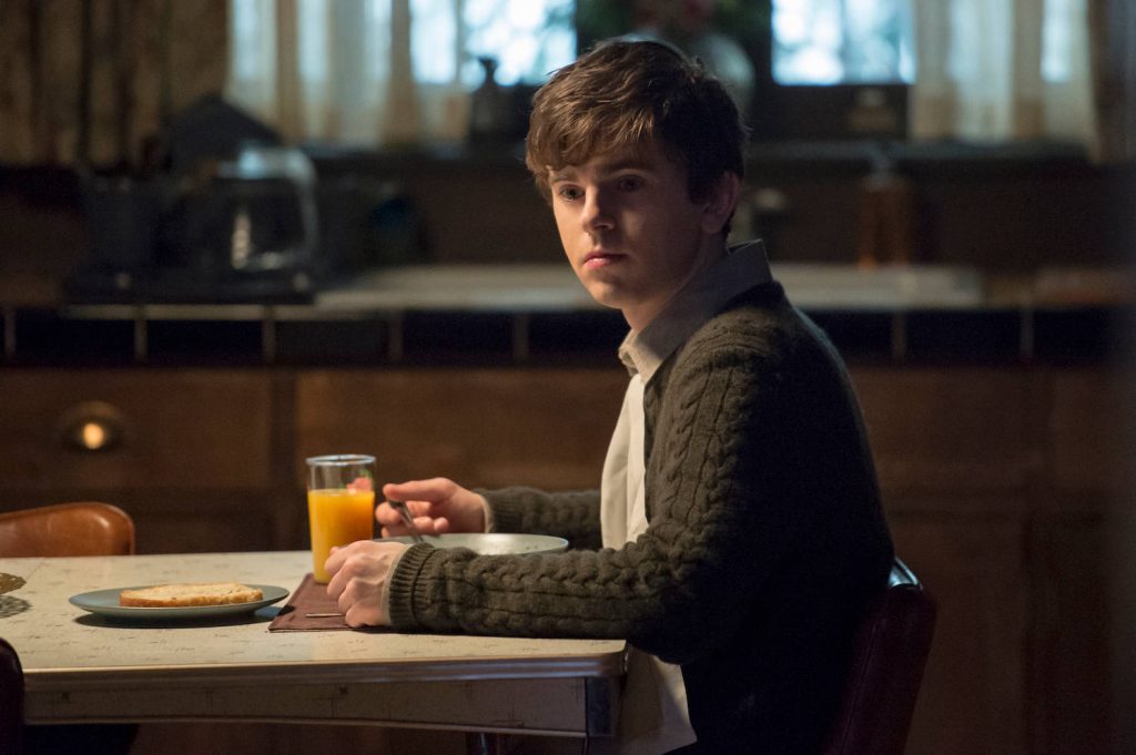Freddie Highmore as Norman Bates in dim kitchen eating meal brooding intense mood Bates Motel wallpaper
