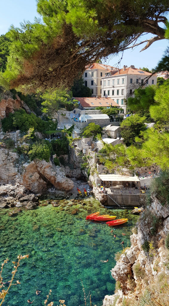 Northern Croatia coastal scene with turquoise waters rocky cliffs green pines stone buildings Wallpaper