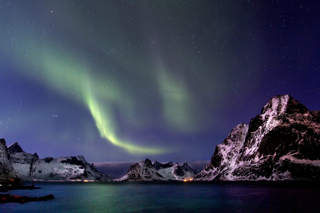 Northern lights over snow-capped mountains calm water starry sky tranquil mystical night landscape Wallpaper