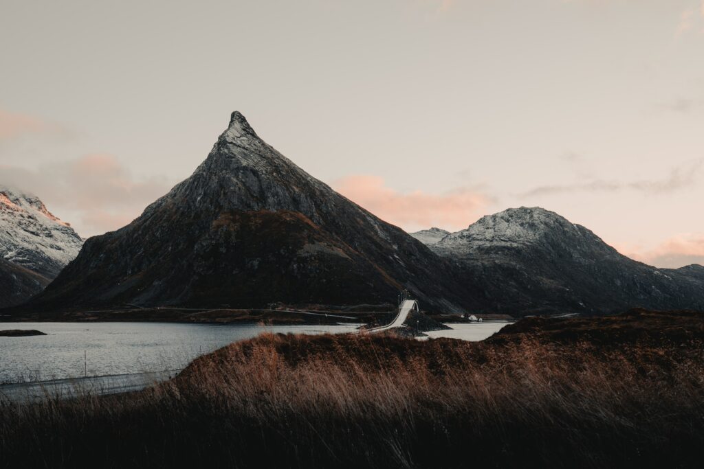 Norwegian landscape with snowy mountains flowing river and modern bridge at sunset wallpaper
