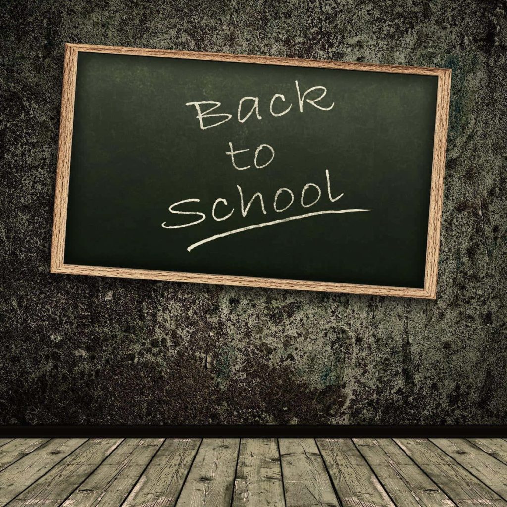 Green chalkboard with white chalk text on stone wall above wooden floorboards classroom scene Wallpaper