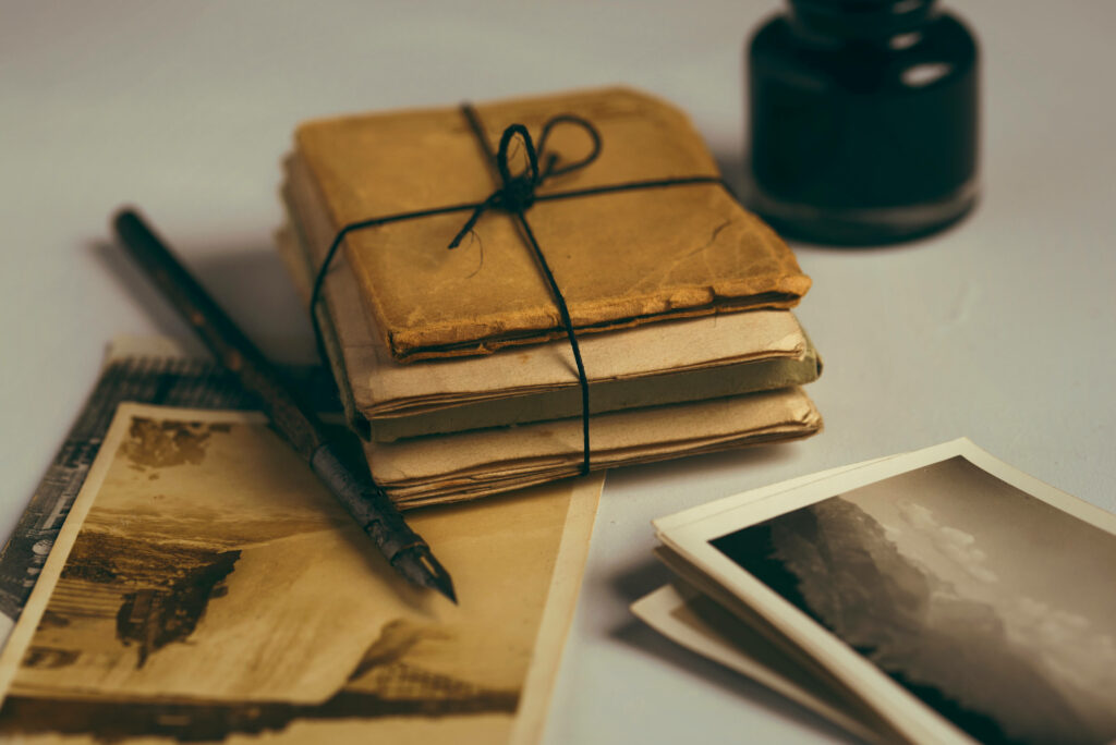 Dark academia wallpaper with vintage letters ink bottle fountain pen and aged photographs in warm light