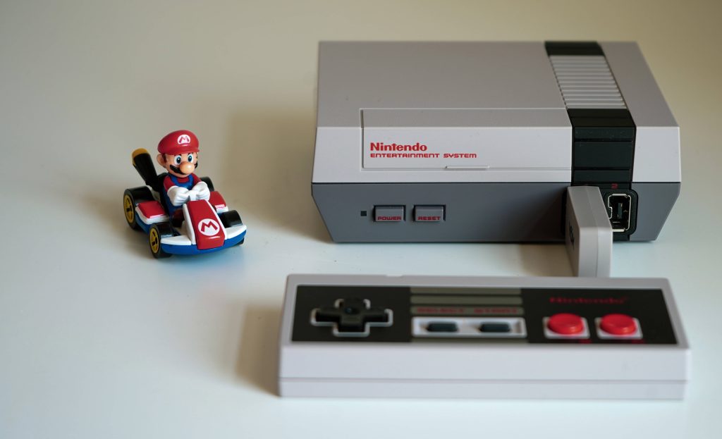 Retro Nintendo NES Classic console and Mario kart figurine on white background wallpaper