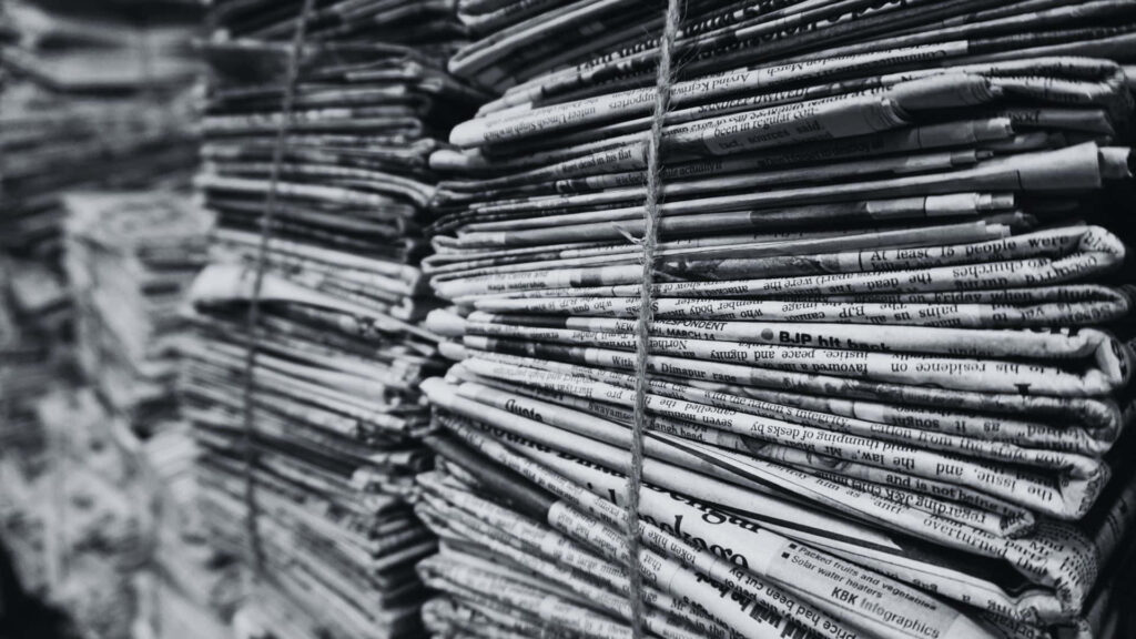 Vintage Black and White Newspapers on Rustic Wooden Table Background Wallpaper