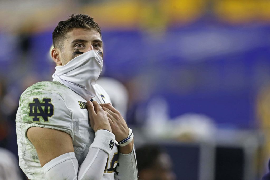 Notre Dame quarterback Ian Book in white uniform with eye black focused football wallpaper background