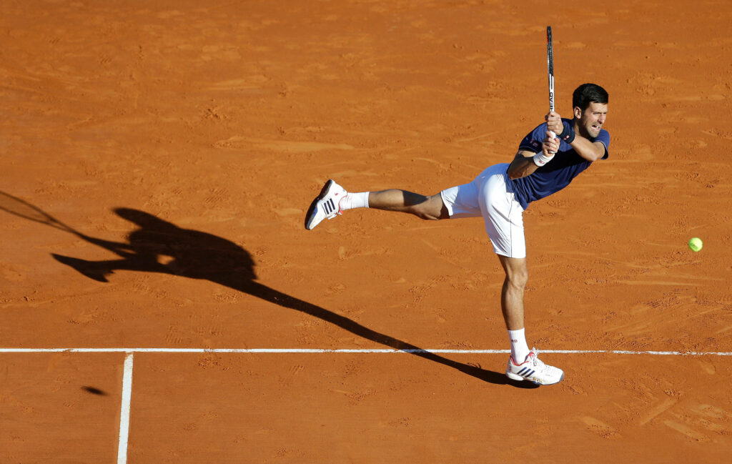 Novak Djokovic in Action on Clay Court - Stunning Wallpaper Background