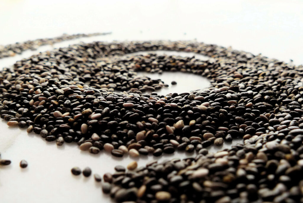 Close-up of nutritious chia seeds in spiral pattern with earthy tones on light background wallpaper
