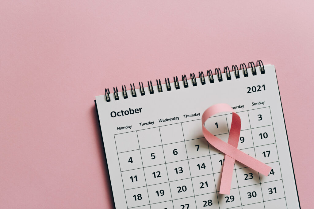 Spiral calendar open to October 2021 with pink breast cancer awareness ribbon on soft pink background Wallpaper