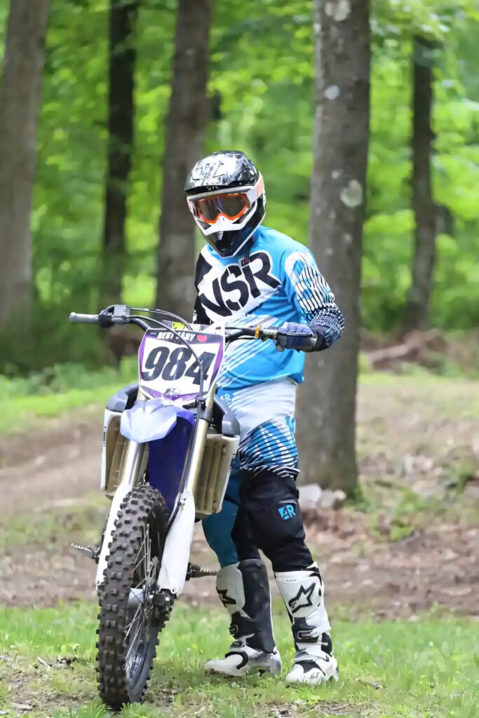 Dirt bike rider in blue MSR gear with bike 984 in green forest off-road adventure wallpaper