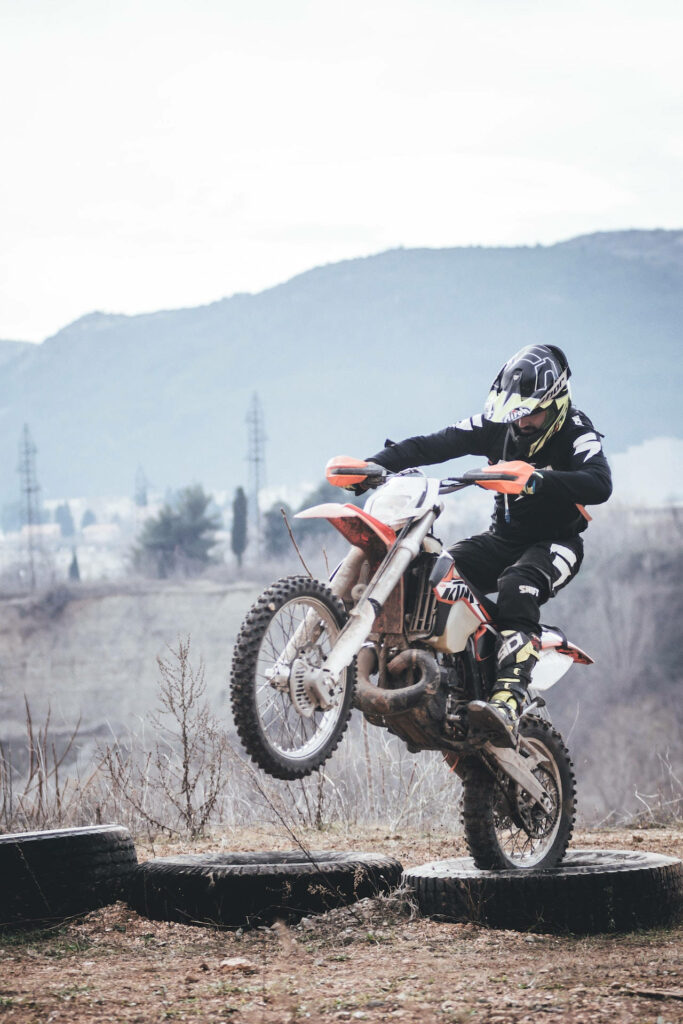 Dirt bike rider mid-jump over rugged hills off-road motocross adventure earthy tones wallpaper