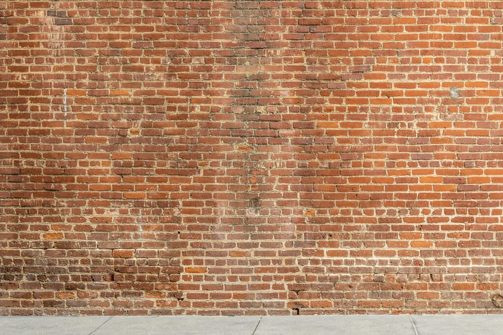 Rugged Elegance: An Old Brick Red Wallpaper Featuring Textured Concrete Wall Composed of Mortarless Bricks - Background Photo