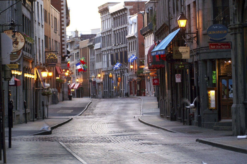 Old Montreal dawn view with historic stone buildings cobblestone streets and warm lamplight Wallpaper