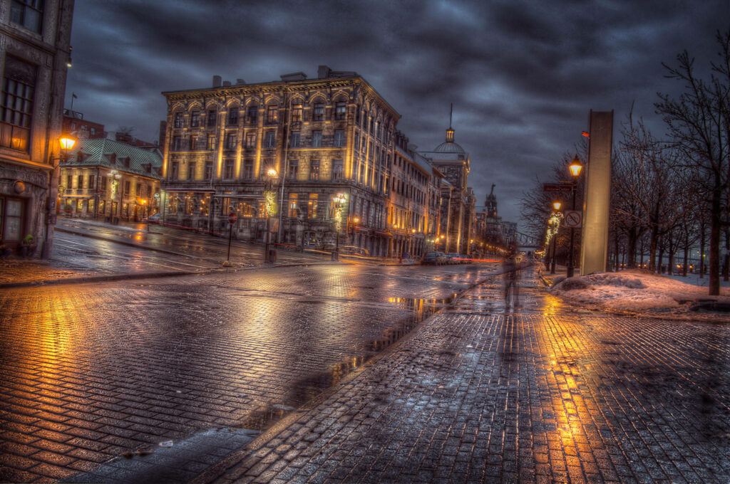 Moody evening Old Montreal streets with glowing lights wet cobblestones historic architecture Wallpaper