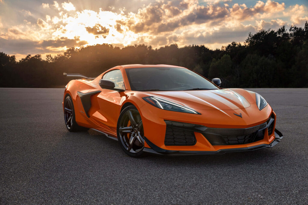Orange Corvette C7 GTR parked on open road at sunset with dramatic cloudy sky wallpaper background