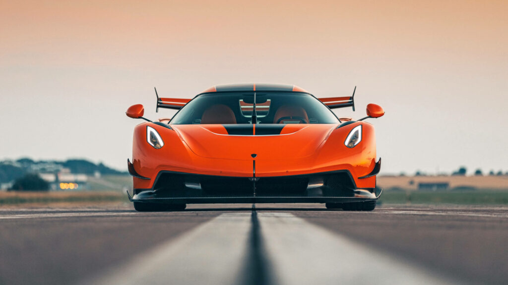 Orange Koenigsegg Jesko supercar front view on open road showcasing aggressive design and speed Wallpaper