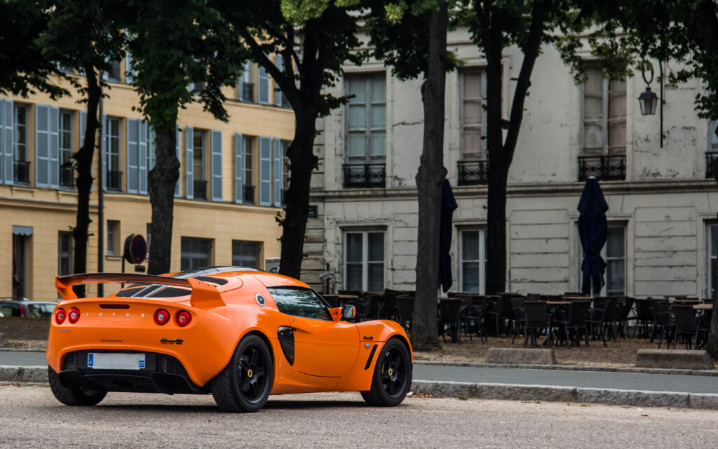 Orange Lotus Exige in Urban Setting - Back View Wallpaper