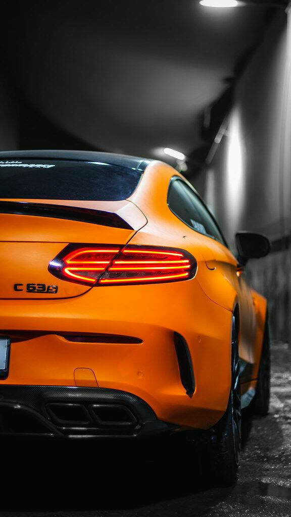Back view of orange Mercedes AMG C63 with illuminated tail lights in urban tunnel wallpaper background