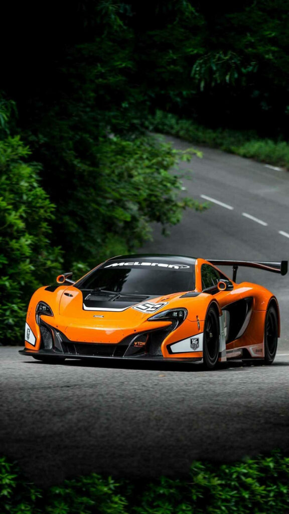Orange sports car speeding on winding road with lush green trees vibrant iPhone wallpaper background