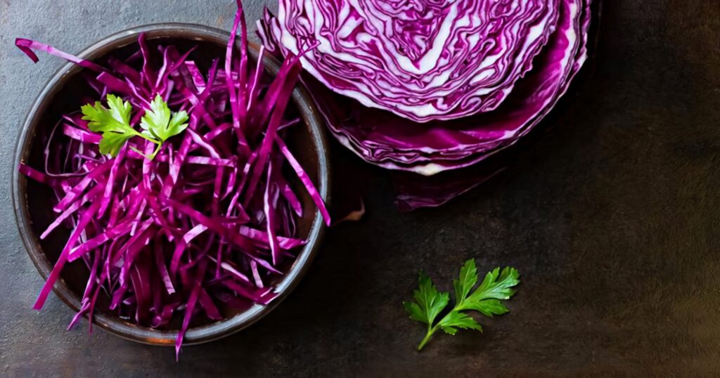 Shredded red cabbage in rustic bowl with fresh parsley and sliced cabbage on dark background Wallpaper