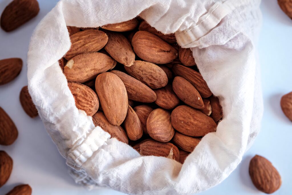 Close-up of organic whole almonds overflowing from a bag showing natural texture and freshness Wallpaper