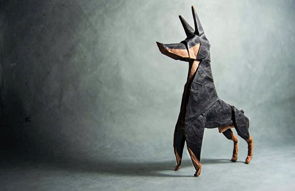 Origami Dobermann wallpaper with sharp geometric folds in black and tan on grey background
