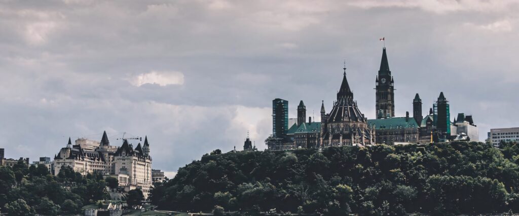 Monochromatic Ottawa Parliament Hill under dramatic cloudy sky with historic architecture and greenery Wallpaper