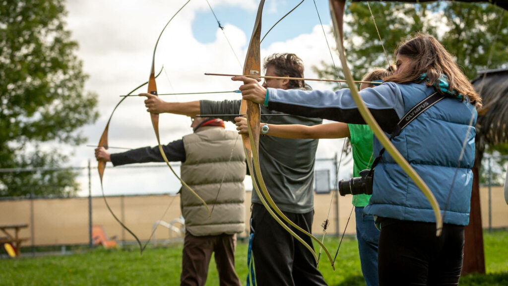 Three Archers Compete Outdoors: Precision & Sportsmanship Wallpaper
