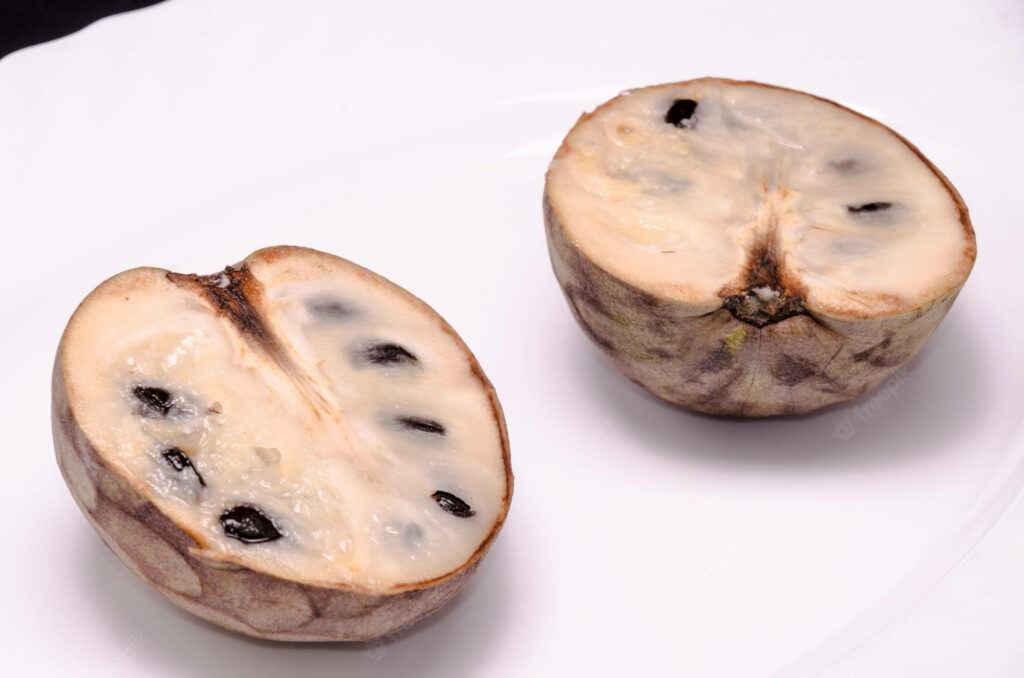 Over-ripened cherimoya halves with creamy texture and black seeds on white background wallpaper