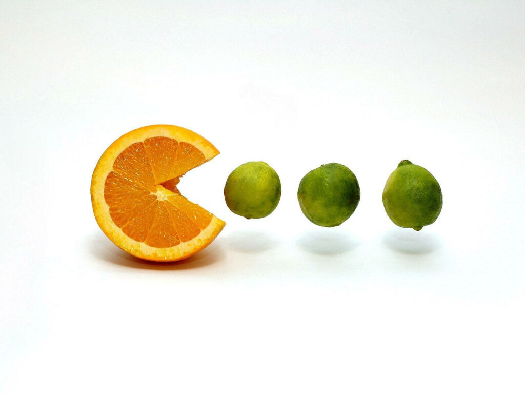 Pac-Citrus Extravaganza: Vibrant Japanese Video Game-inspired Fruit Art on White Desktop Wallpaper