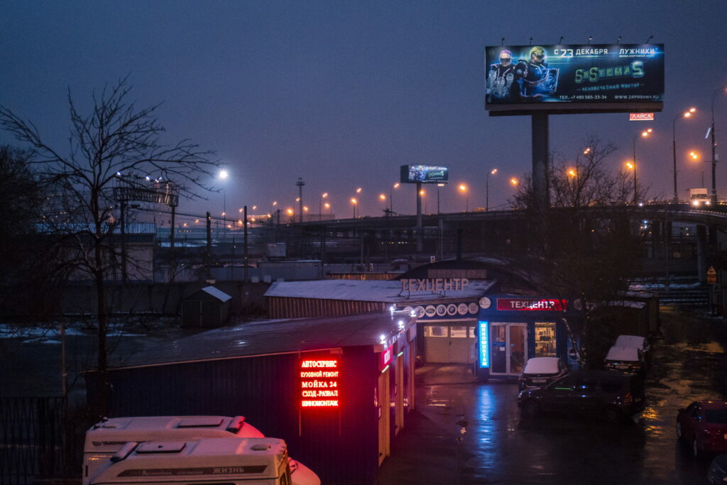 Moody evening Moscow car repair shop with neon red blue lights cyberpunk cityscape wallpaper