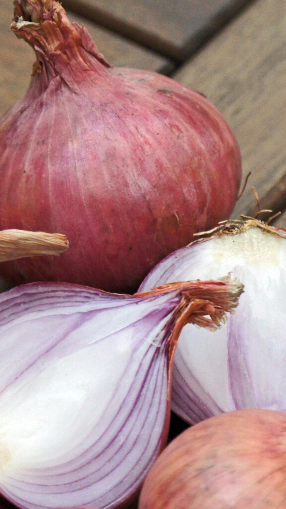Pale Red Onions Close-Up: Rustic Wooden Plank Wallpaper Background
