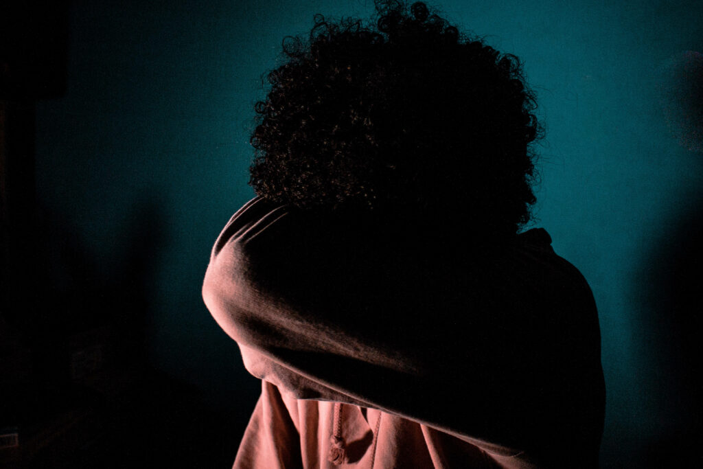 Gloomy Solitude: Edgy Depiction of a Man Embracing Isolation in Pink Pullover Wallpaper