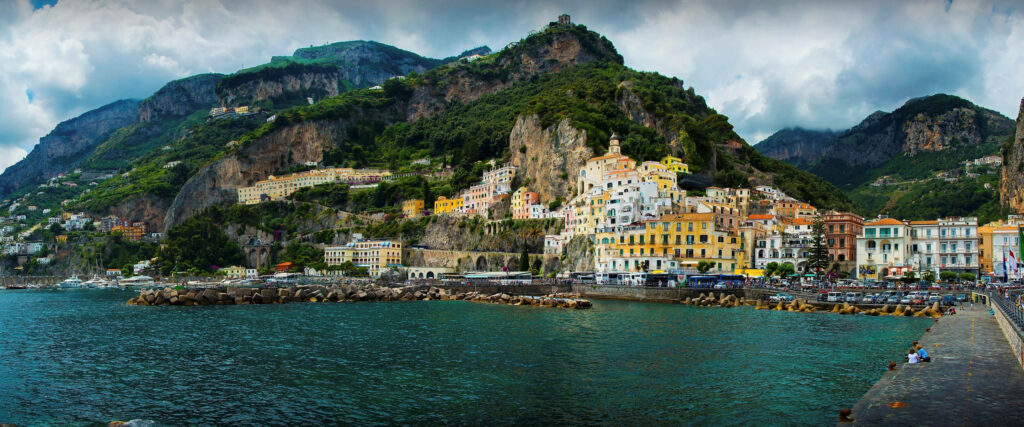 Panoramic Amalfi Coast view with vibrant seaside buildings cliffs green mountains Mediterranean sea Wallpaper