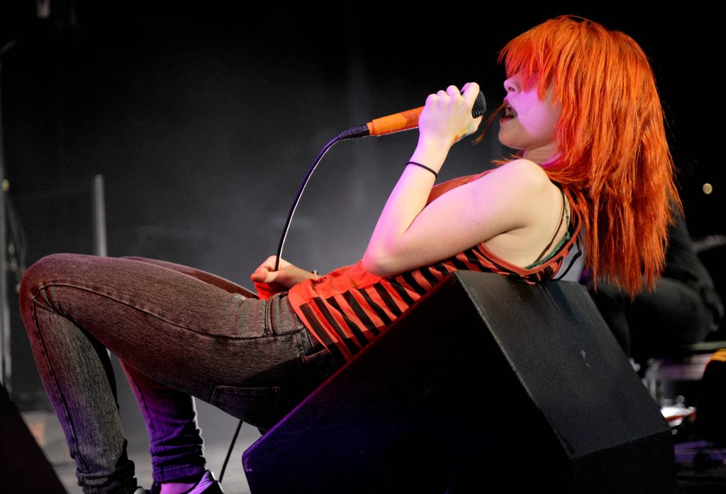 Hayley Williams with iconic orange hair performing live at Paramore concert vibrant rock star wallpaper