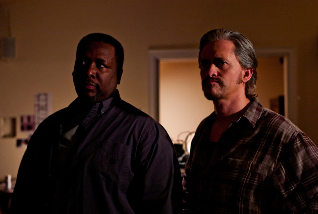 Wendell Pierce and Clifton Collins Jr. in tense scene from 2013 Parker thriller with dramatic wallpaper