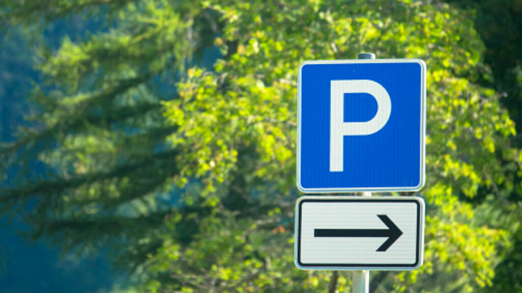 Serene Parking Sign Wallpaper with Blue Background & Green Foliage